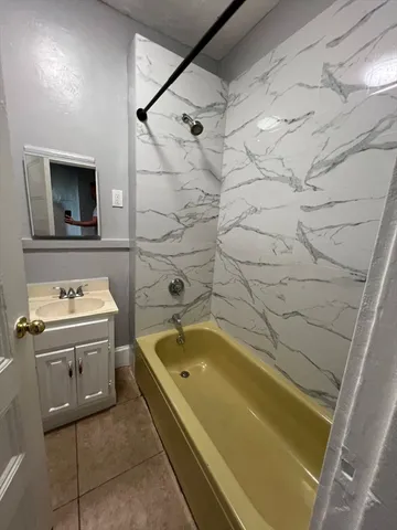 a bathroom with a tub sink and mirror