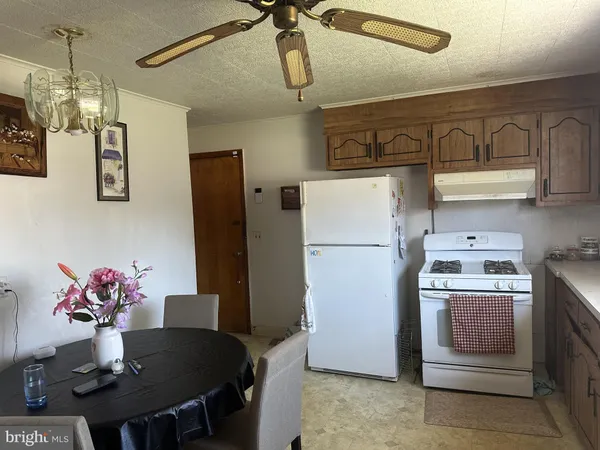 a kitchen with stainless steel appliances granite countertop a refrigerator a sink dishwasher a dining table and chairs with wooden floor