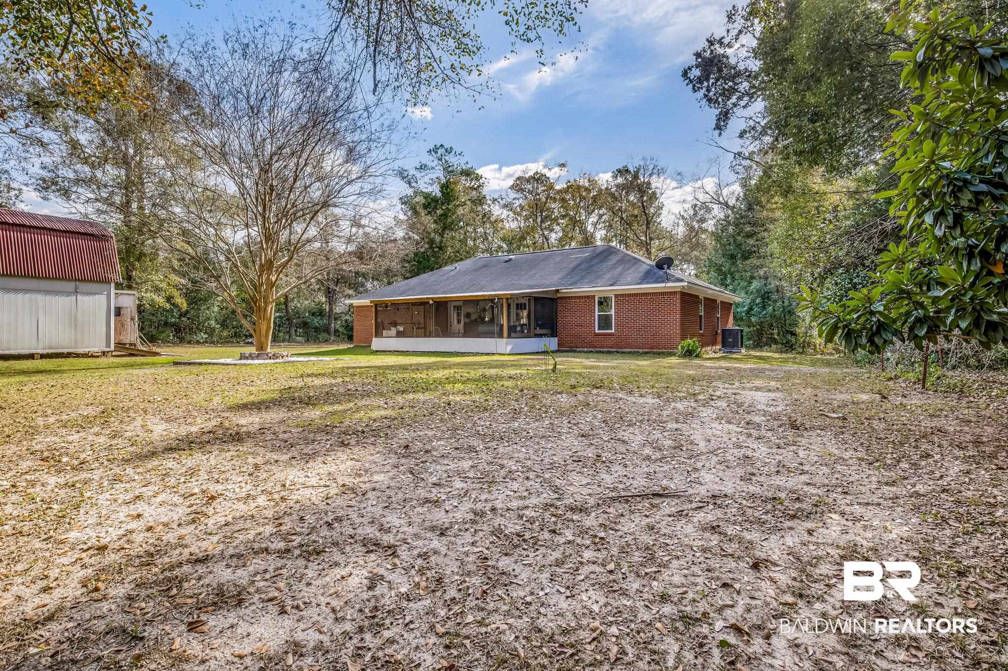 12199 Bay Road West Foley, AL 36535 - Photo 10 of 62 Rear view of property with a sunroom, brick siding, a yard, and view of wooded area