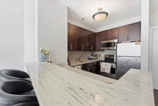 a kitchen with granite countertop a stove a sink a refrigerator and a microwave