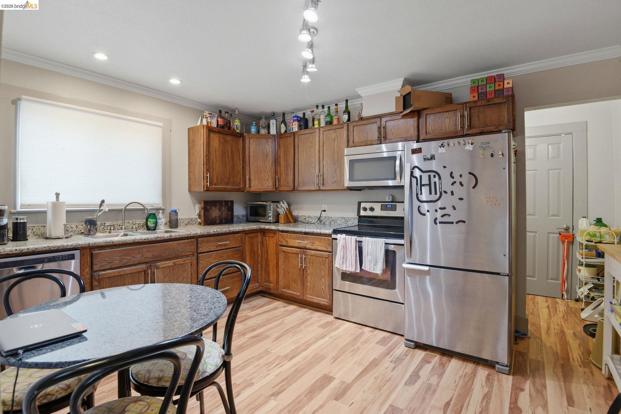 2155 Chestnut Street Livermore, CA 94551 - Photo 10 of 44 Kitchen featuring stainless steel appliances, light wood-style floors, wood finish cabinetry, and ornamental molding