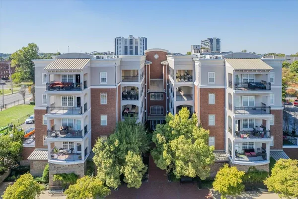 a front view of a multi story residential apartment building with a yard and outdoor seating