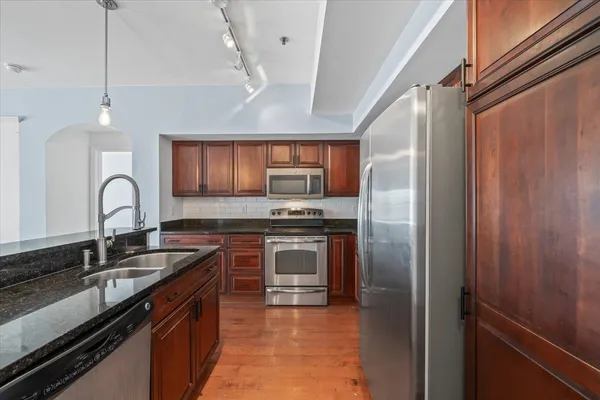 a kitchen with granite countertop a sink stainless steel appliances and cabinets