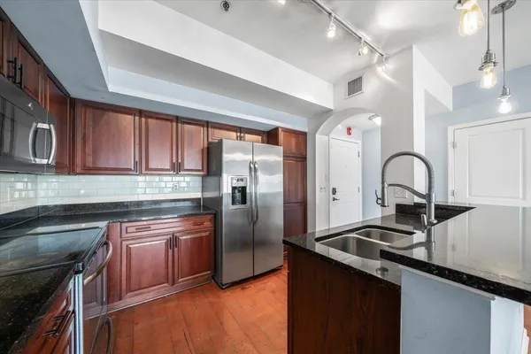 a kitchen with granite countertop a sink stainless steel appliances and cabinets