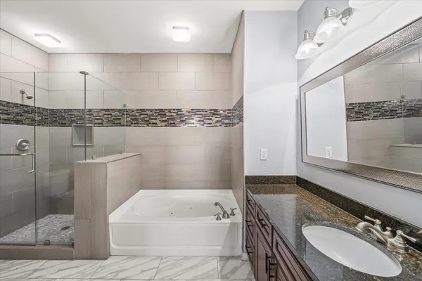 a bathroom with a granite countertop sink a mirror and bathtub