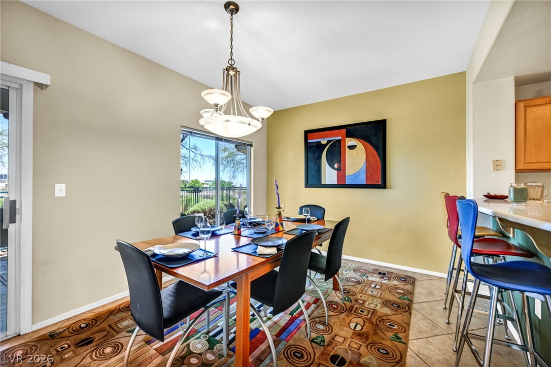 10730 Amber Ridge Drive, Unit 101 Las Vegas, NV 89144 - Photo 10 of 32 Natural light illuminates this dining area with an overhead chandelier and access to an outdoor space.