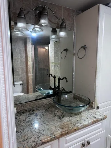 a bathroom with a granite countertop sink a mirror and shower