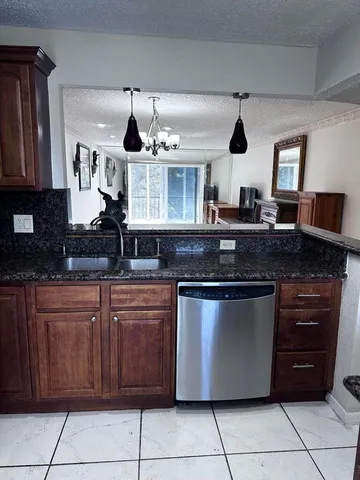 a kitchen with granite countertop a refrigerator stove and sink