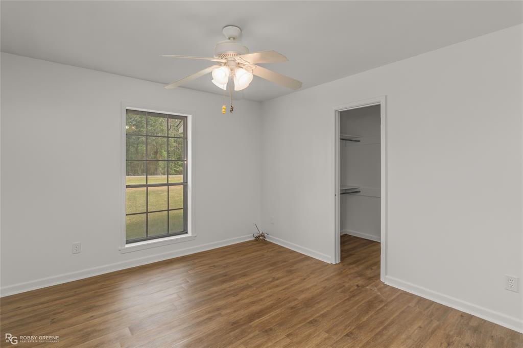 1303 Young Road Benton, LA 71006 - Photo 20 of 34 Unfurnished bedroom with a spacious closet, dark wood-style flooring, and a ceiling fan