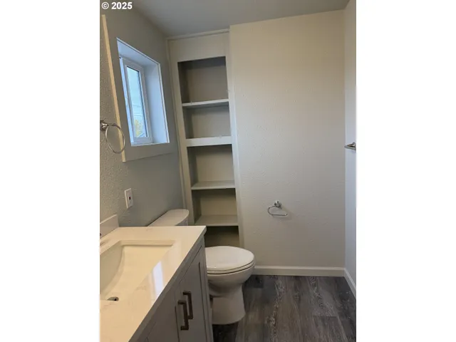a bathroom with a toilet a sink and wooden floor