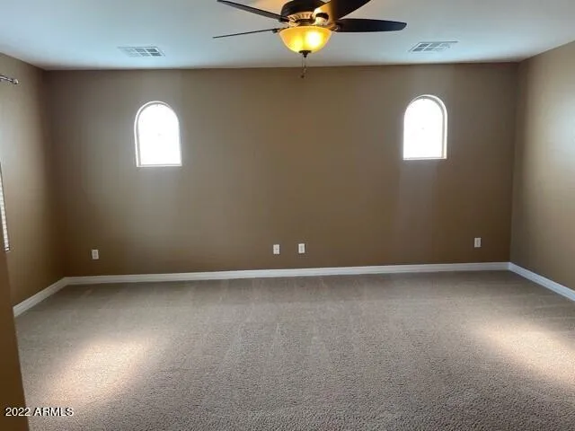an empty room with a chandelier fan and windows