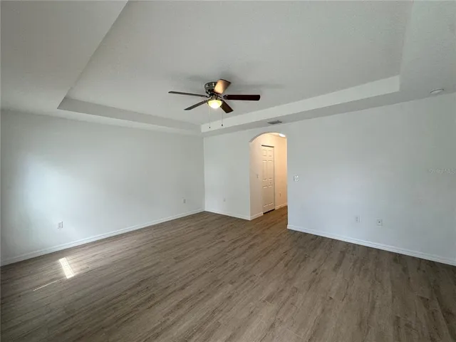 an empty room with wooden floor and a ceiling fan