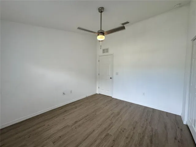 a view of a room with wooden floor and ceiling fan