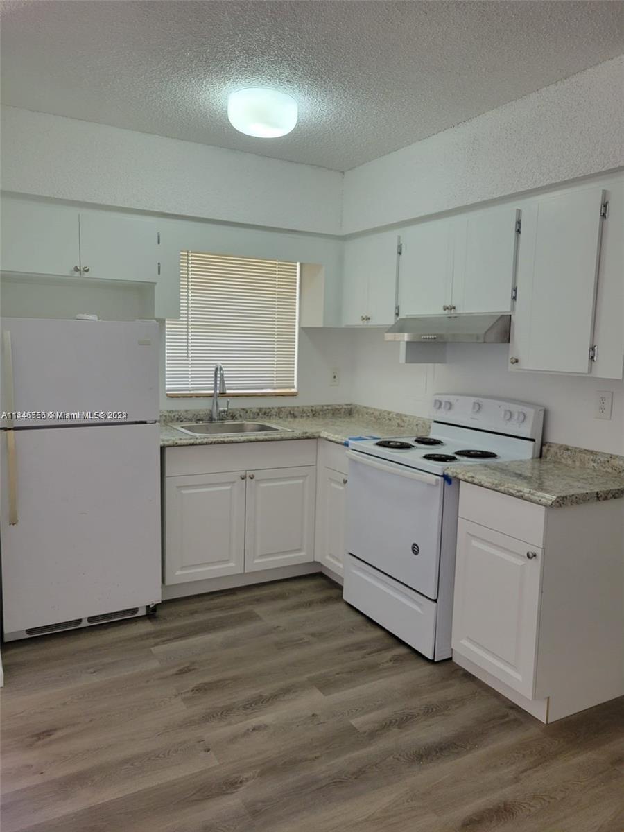 1755 Northeast 116th Road, Unit 9 North Miami, FL 33181 - Photo 2 of 27 a white kitchen with granite countertop white cabinets and white appliances