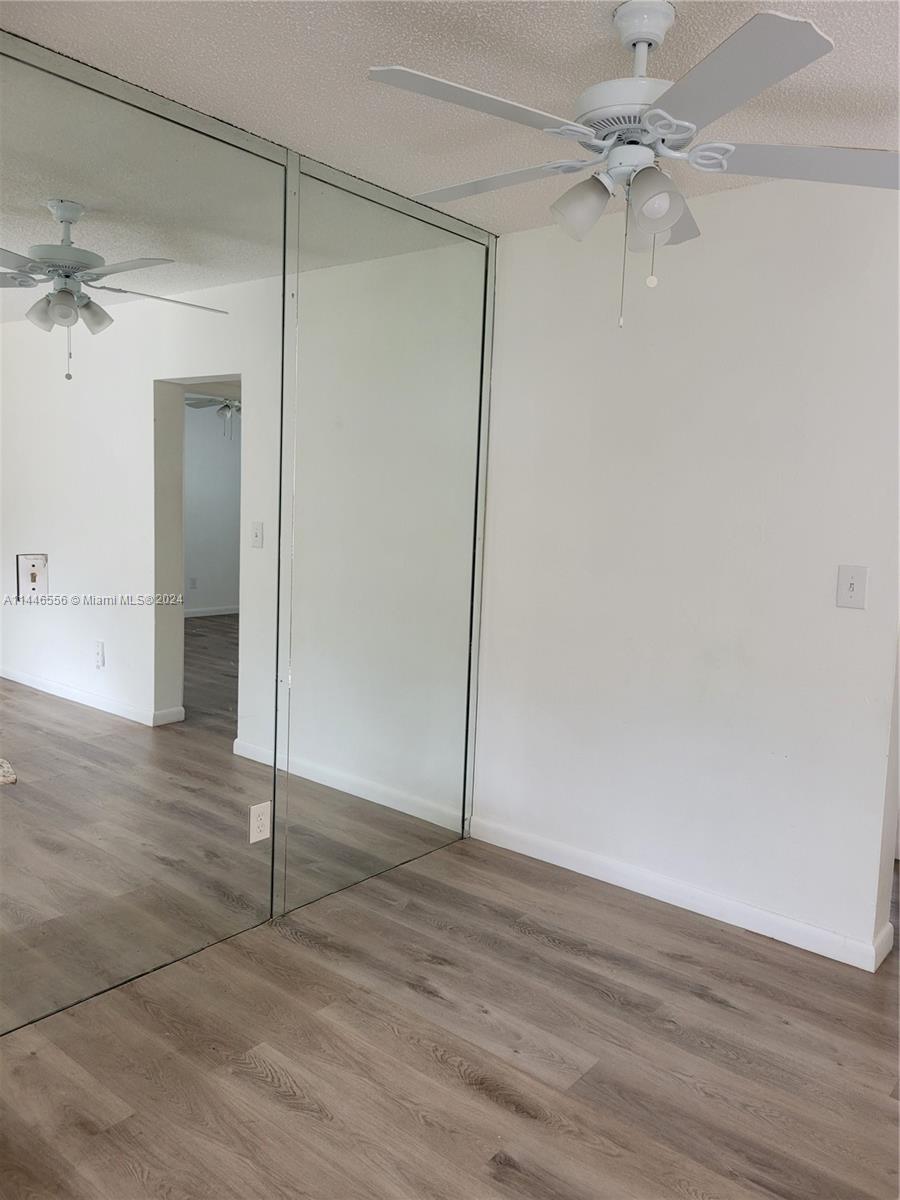 1755 Northeast 116th Road, Unit 9 North Miami, FL 33181 - Photo 7 of 27 an empty room with wooden floor and fan