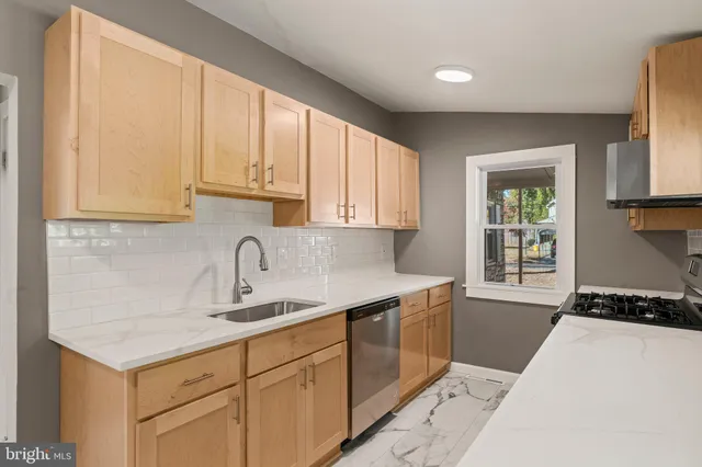 a kitchen with granite countertop a sink a stove cabinets and a window