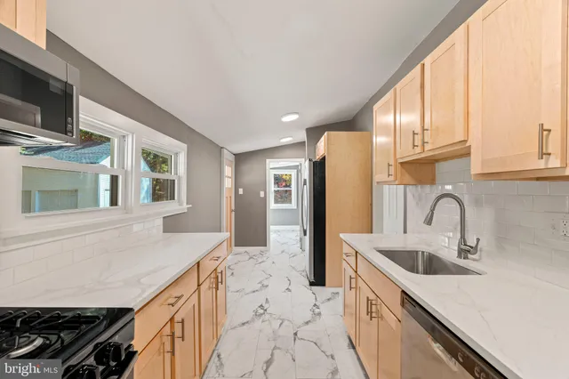 a kitchen with kitchen island granite countertop a sink appliances cabinets and a counter top space