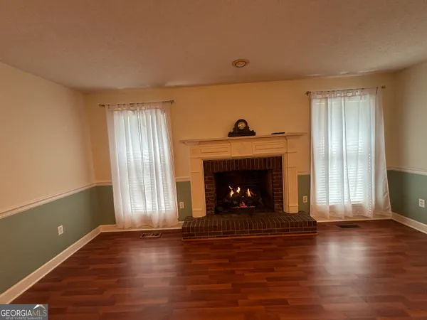 a kitchen with stainless steel appliances a stove a refrigerator a sink a dining table and chairs with wooden floor