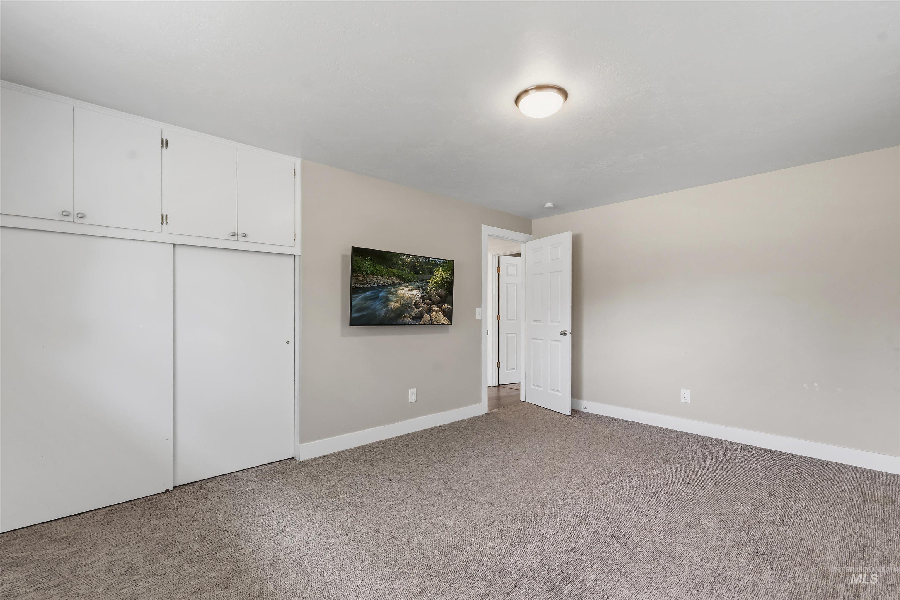 355 East Beacon Light Road Eagle, ID 83616 - Photo 17 of 47 Carpeted room featuring a built-in white wardrobe with sliding doors and overhead cabinetry, neutral painted walls, white trim, and a ceiling-mounted light fixture
