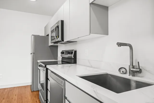a kitchen with a sink and a stove top oven with wooden floor