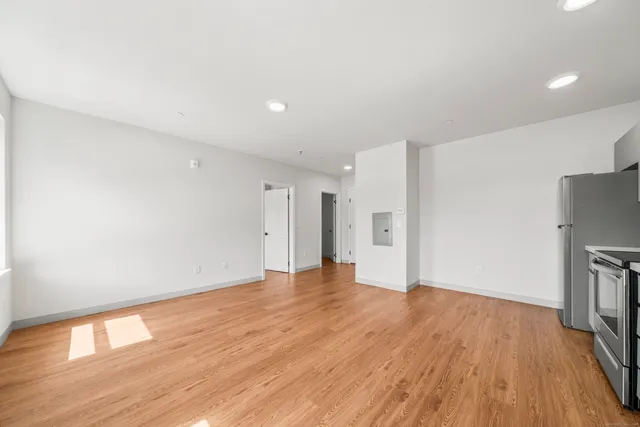 a view of an empty room with wooden floor and a window