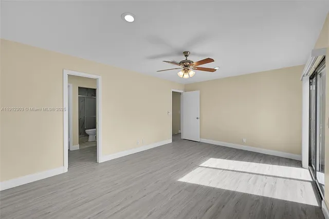 an empty room with wooden floor and chandelier fan