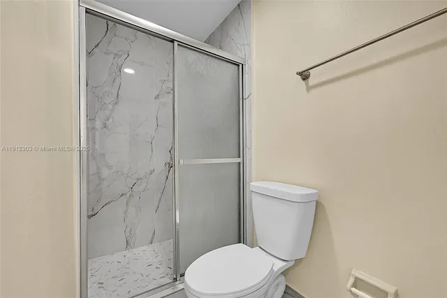 a white toilet sitting next to a shower