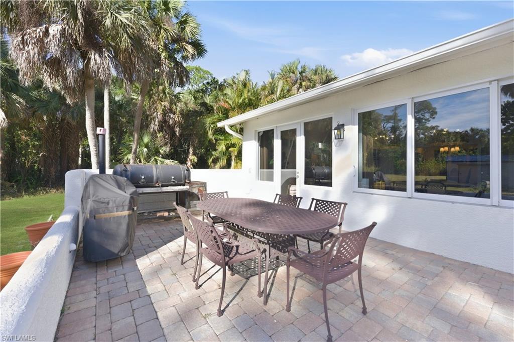 4630 11th Avenue Southwest Naples, FL 34116 - Photo 39 of 50 a view of a patio with table and chairs and floor to ceiling window