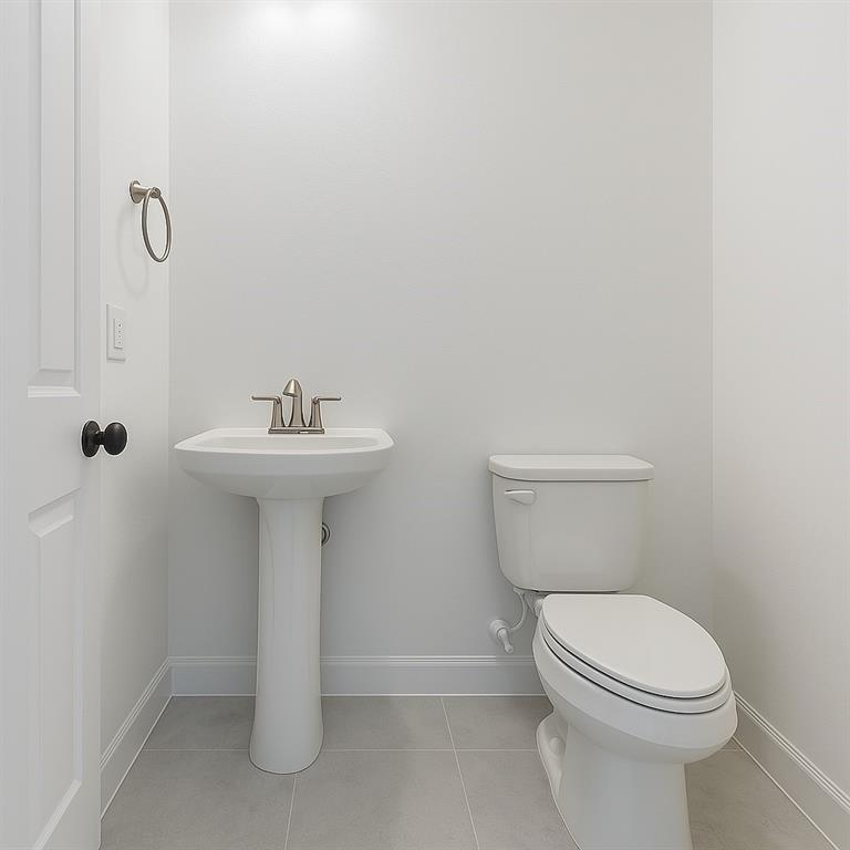 1733 Dalhart Road Plano, TX 75075 - Photo 10 of 20 Pedestal sink with a brushed nickel faucet, white toilet, light gray tile flooring, and a white interior door with a black knob