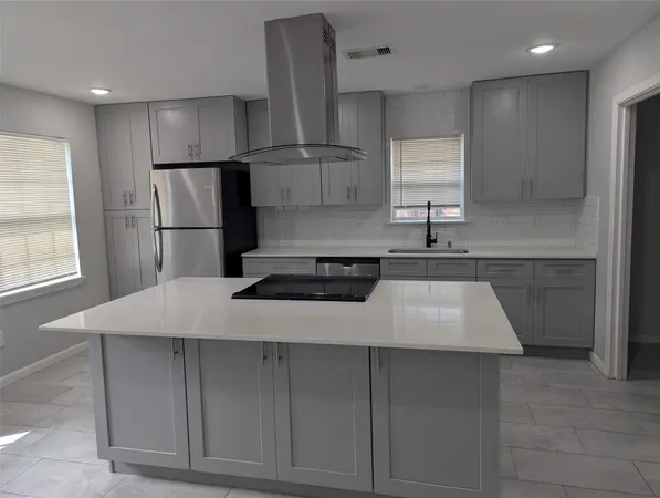 a kitchen with kitchen island granite countertop a sink a stove a refrigerator and island