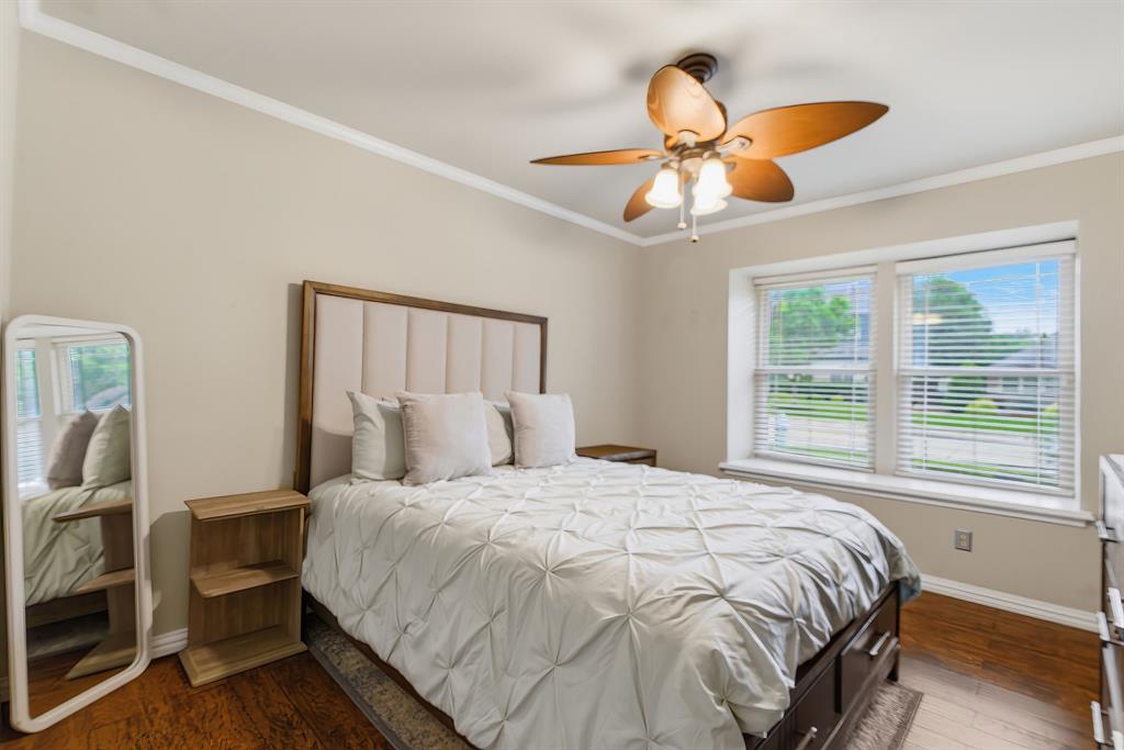 2307 Castle Rock Road Carrollton, TX 75007 - Photo 25 of 34 This bedroom features hardwood floors, a ceiling fan with light fixture, and two windows providing natural light