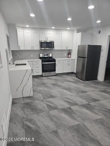 a kitchen with a refrigerator a stove top oven and white cabinets