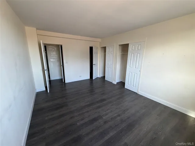 a view of an empty room with wooden floor and closet