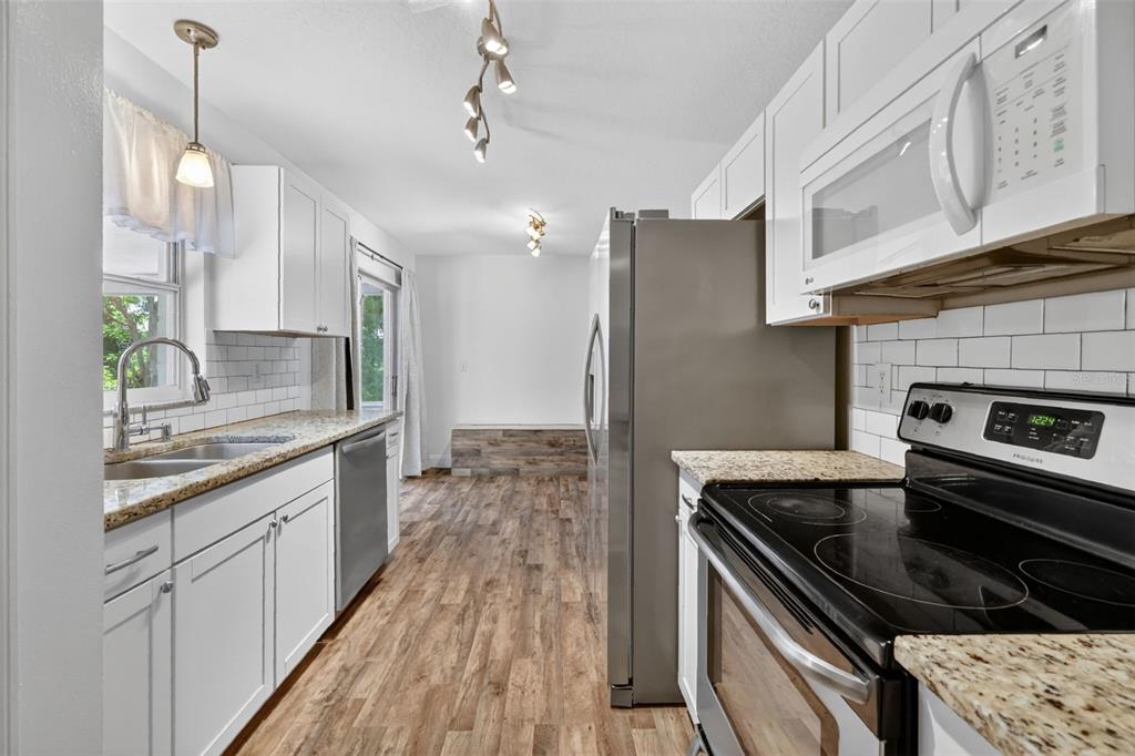 36 Bay Ridge Loop Mascotte, FL 34753 - Photo 16 of 32 a kitchen with stainless steel appliances kitchen island granite countertop a stove a sink dishwasher and a refrigerator with wooden floor