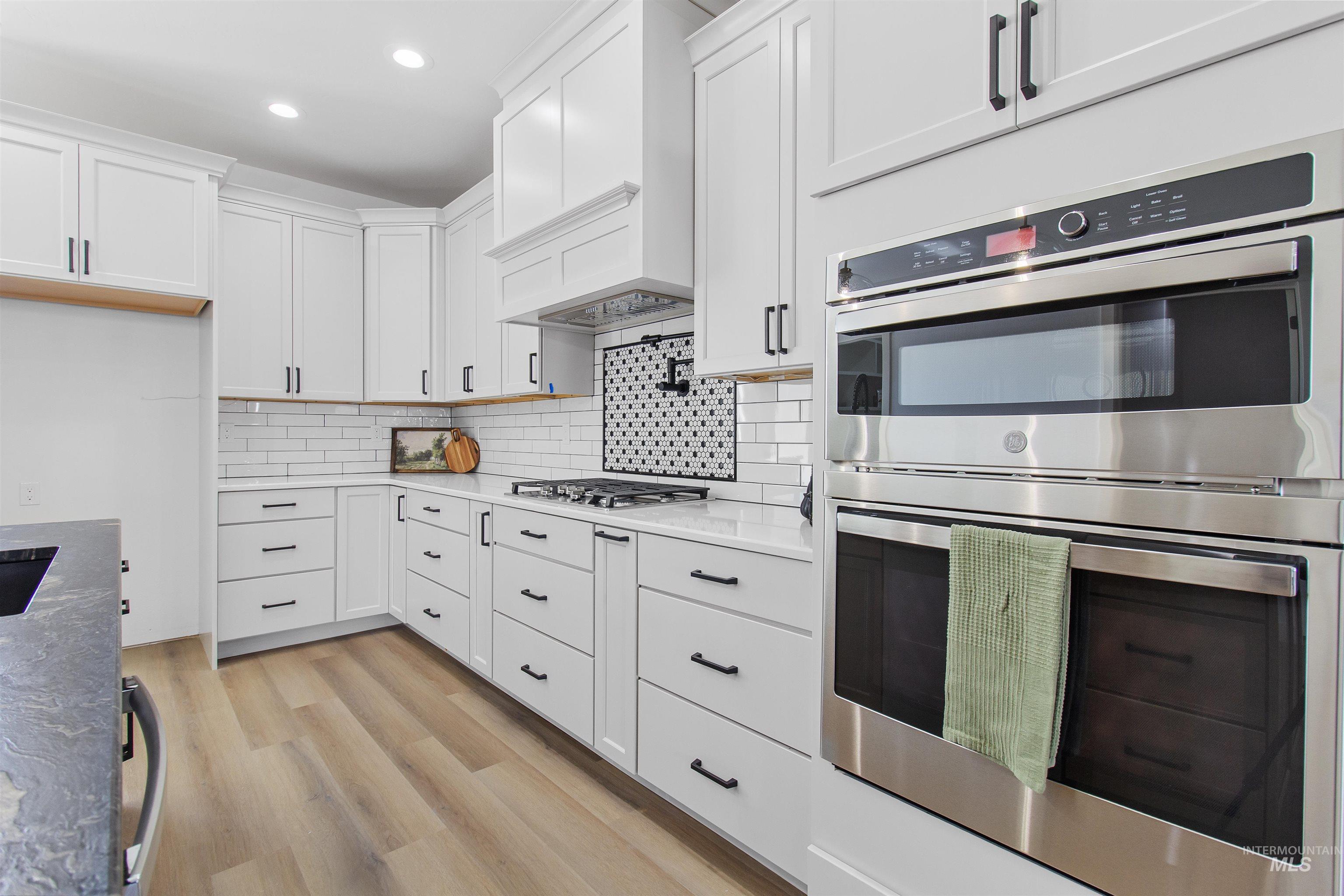 514 Full Moon Way Twin Falls, ID 83301 - Photo 13 of 49 Kitchen with stainless steel appliances, white cabinets, light wood-style flooring, tasteful backsplash, and recessed lighting
