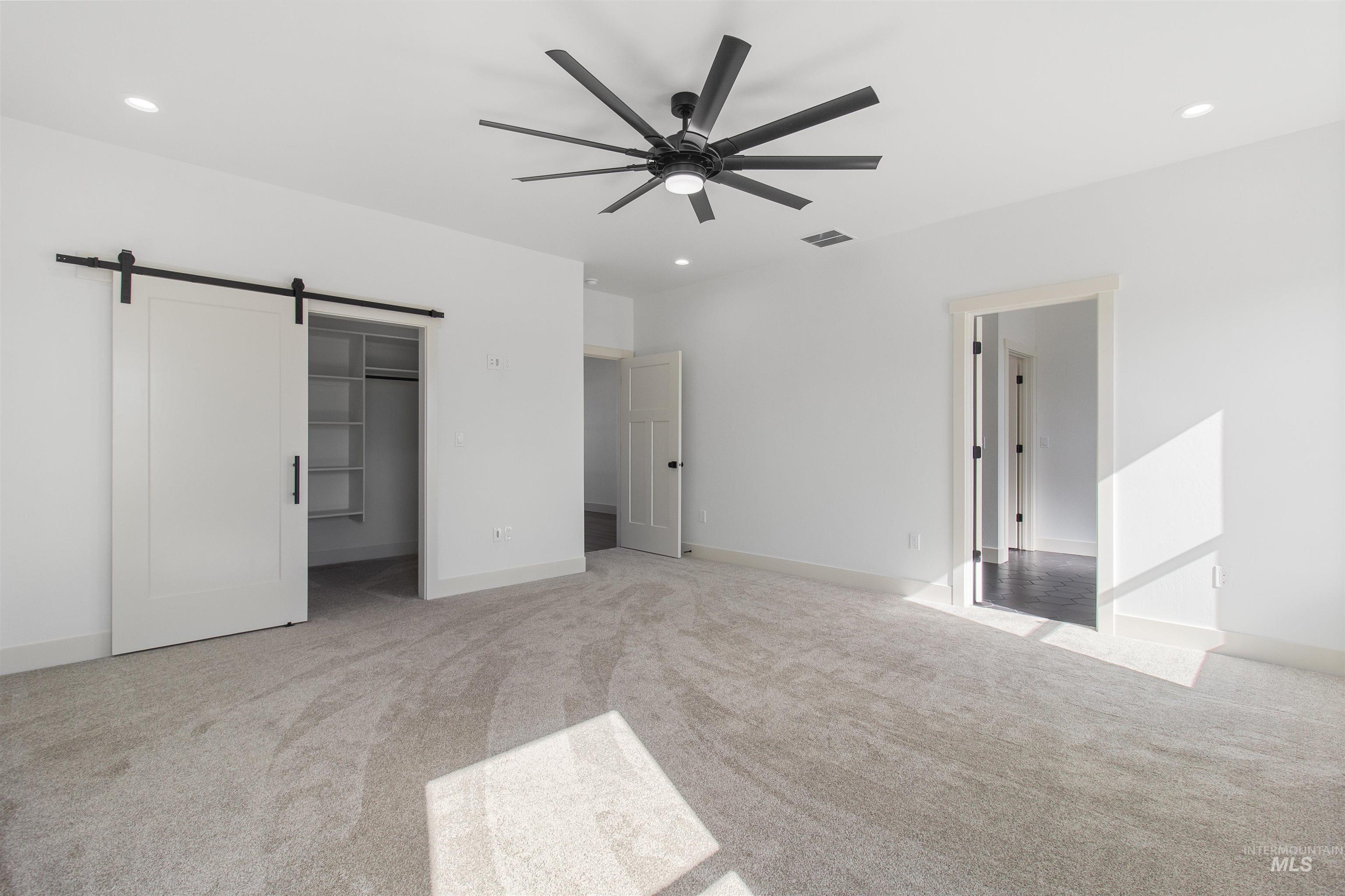 514 Full Moon Way Twin Falls, ID 83301 - Photo 18 of 49 Unfurnished bedroom with a barn door, a spacious closet, light carpet, a ceiling fan, and recessed lighting