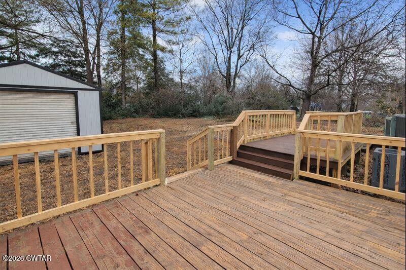 a view of wooden deck and a yard with wooden fence