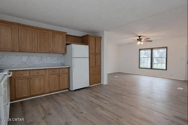an empty room with wooden floor cabinet and windows