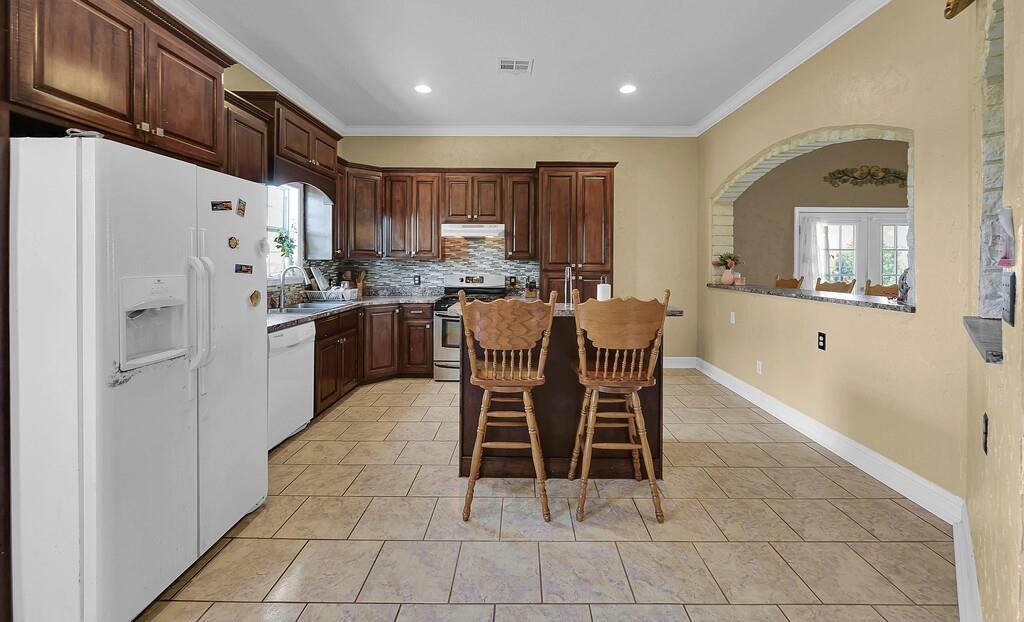 355 Highway 236 Moody, TX 76557 - Photo 21 of 36 Kitchen with white appliances, a sink, ornamental molding, arched walkways, and decorative backsplash