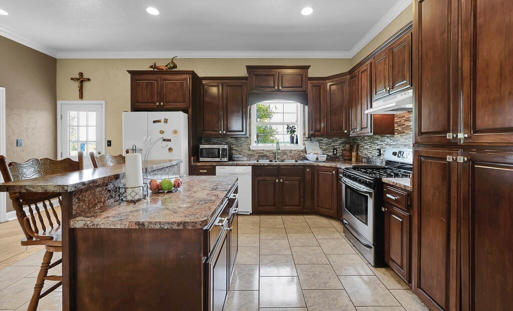 355 Highway 236 Moody, TX 76557 - Photo 22 of 36 Kitchen featuring appliances with stainless steel finishes, a sink, under cabinet range hood, a kitchen bar, and a kitchen island