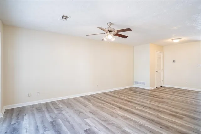 a view of empty room with wooden floor and ceiling fan