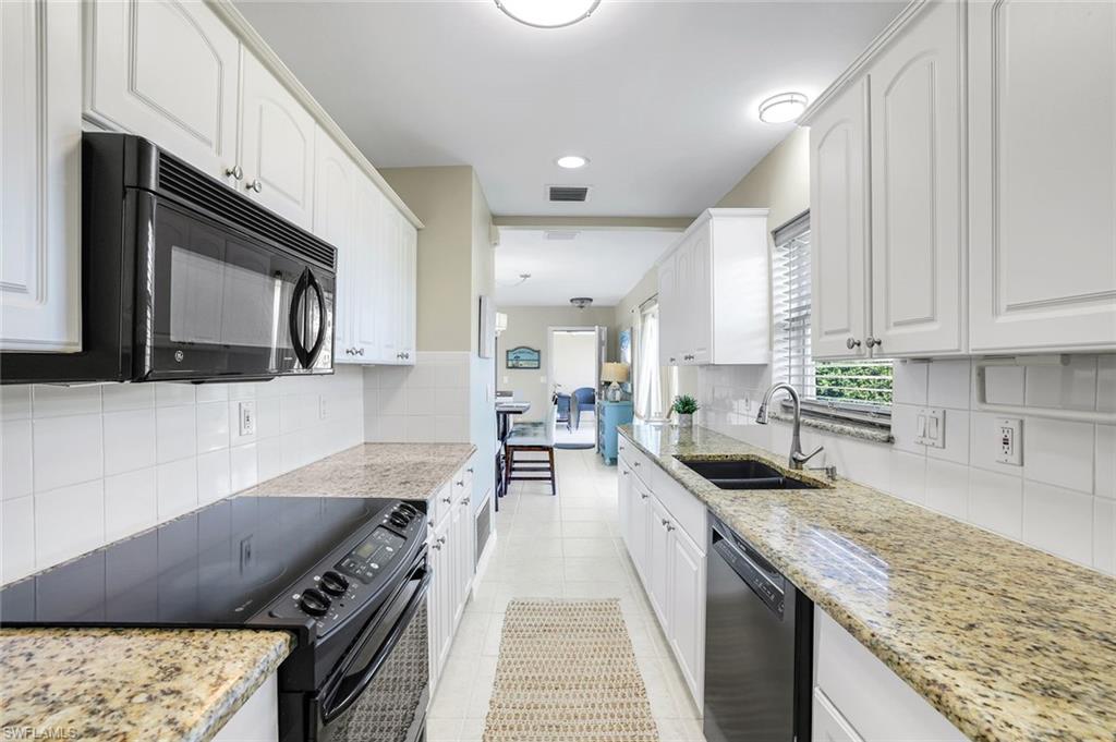 1237 Jamaica Road Marco Island, FL 34145 - Photo 11 of 26 a kitchen with stainless steel appliances granite countertop a stove a sink and a microwave
