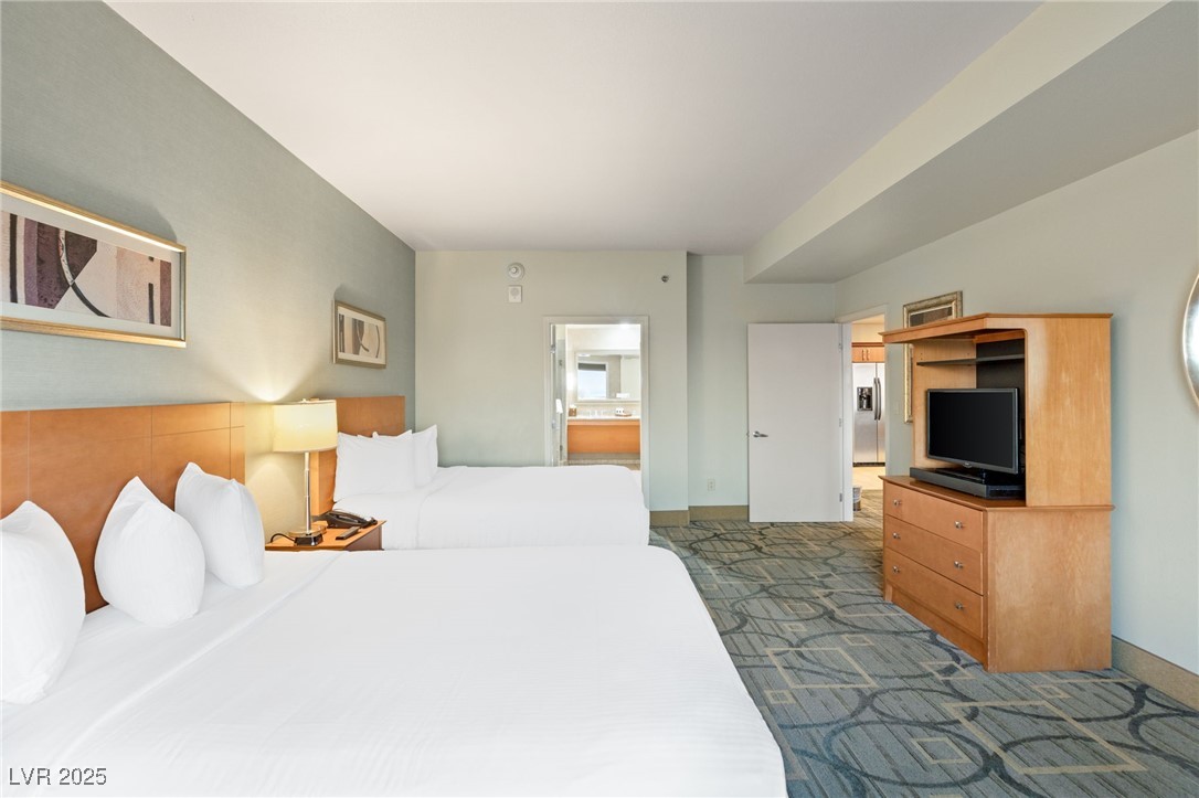 211 East Flamingo Road, Unit 610 Las Vegas, NV 89169 - Photo 13 of 42 Bedroom featuring stainless steel fridge with ice dispenser, dark carpet, ensuite bath, and baseboards