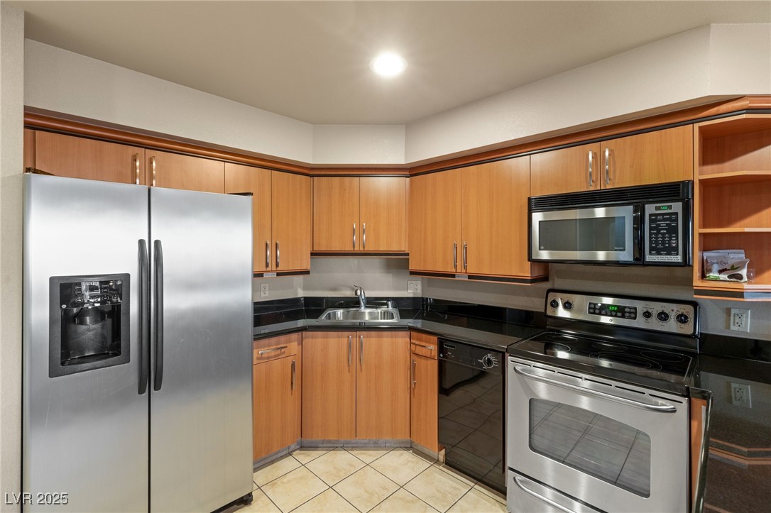 211 East Flamingo Road, Unit 610 Las Vegas, NV 89169 - Photo 8 of 42 Kitchen featuring light tile patterned floors, dark countertops, appliances with stainless steel finishes, brown cabinetry, and a sink
