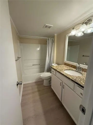 a bathroom with a granite countertop sink a toilet a mirror and shower