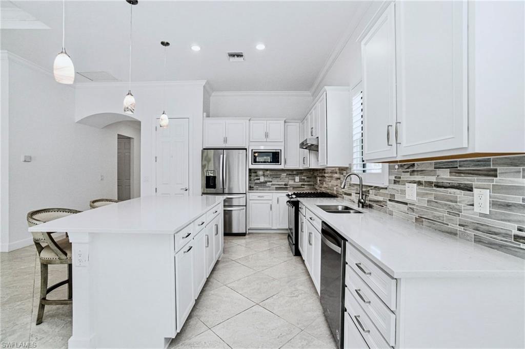 9395 Greyhawk Trail Naples, FL 34120 - Photo 6 of 37 CONTEMPORARY "NATURAL GAS" KITCHEN is beautifully appointed with crisp WHITE CABINETRY, QUARTZ COUNTERS,MARBLED BACKSPLASH in warm earth tones, and stainless-steel appliances, including a gas range.