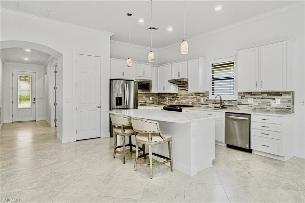 9395 Greyhawk Trail Naples, FL 34120 - Photo 7 of 37 a kitchen with white cabinets and stainless steel appliances