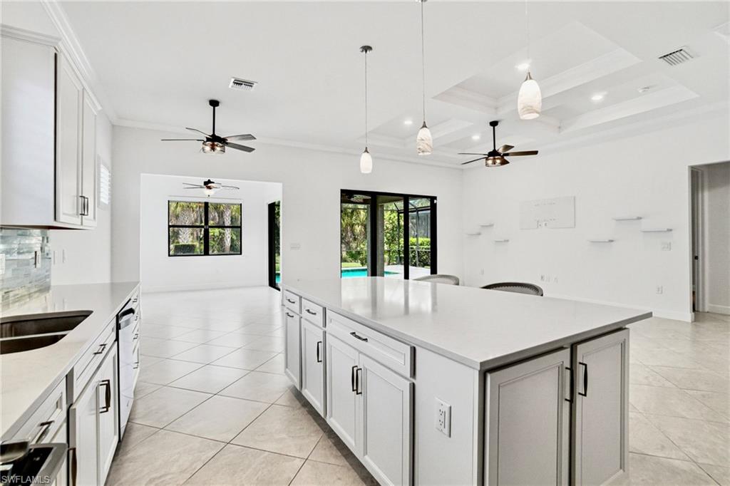 9395 Greyhawk Trail Naples, FL 34120 - Photo 9 of 37 a large white kitchen with a stove a sink a refrigerator and a center island