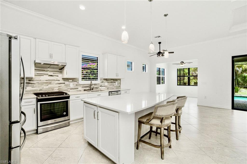9395 Greyhawk Trail Naples, FL 34120 - Photo 10 of 37 a kitchen with stainless steel appliances kitchen island granite countertop a stove a sink a oven a dining table and chairs