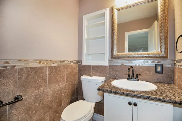 a bathroom with a granite countertop sink a toilet and mirror